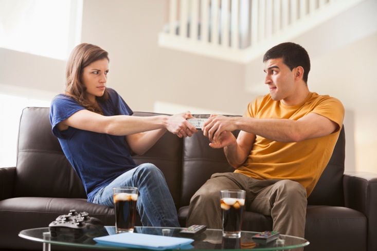 Couple arguing over remote on sofa